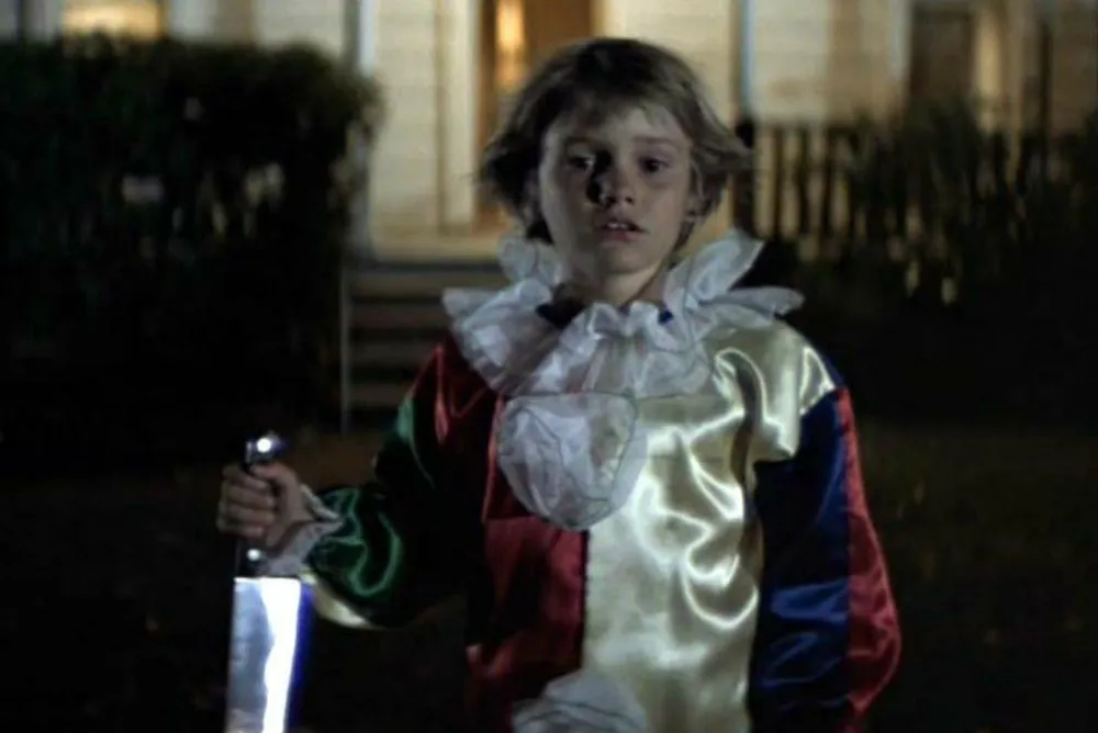 Michael Meyers as a child with a knife and a clown costume